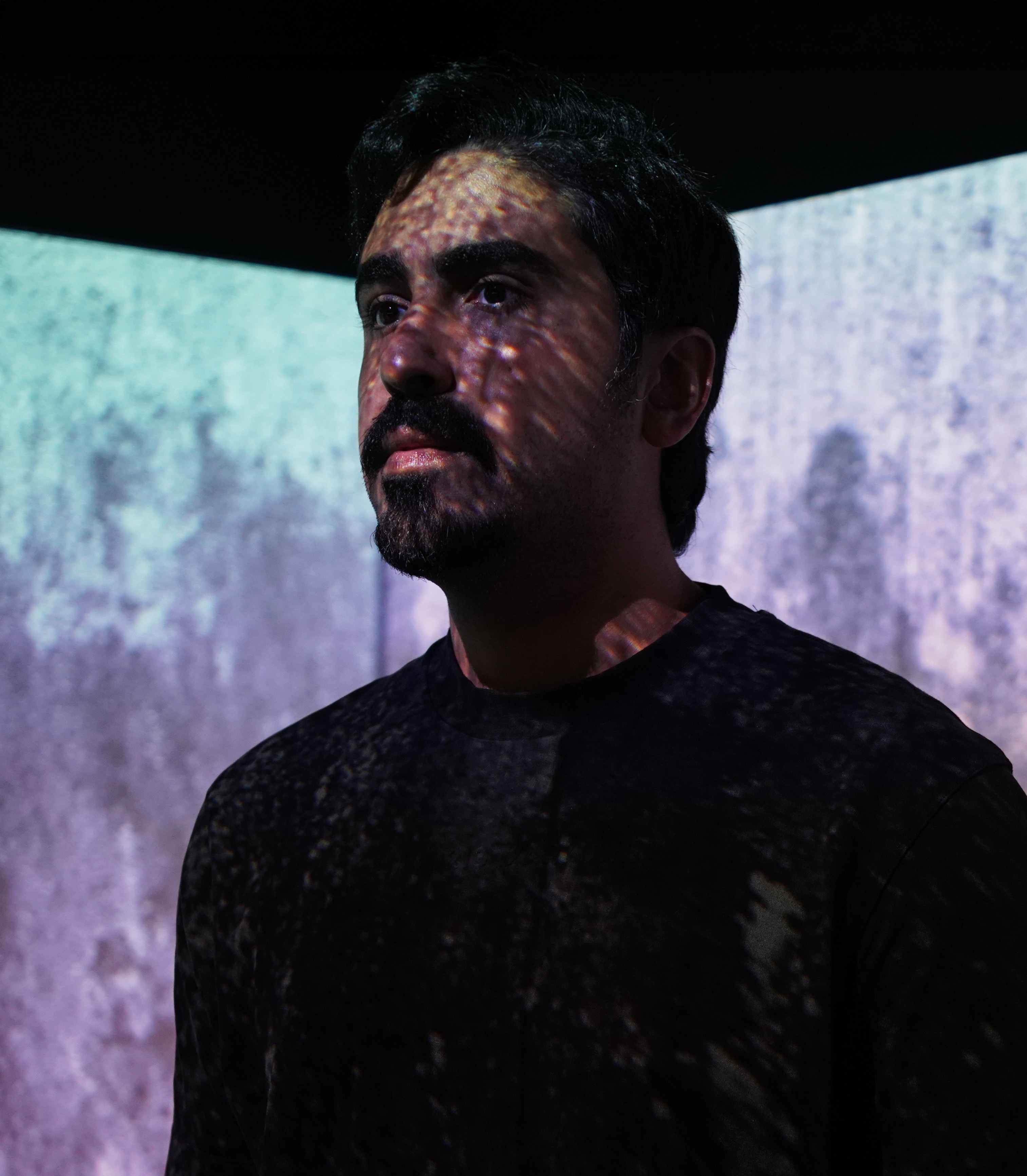 Portrait of Abdullah Al-Wazzan, Kuwaiti filmmaker, in projected light